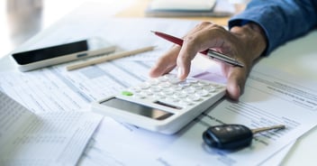 Close up of a person using a calculator to work on dealership finances.