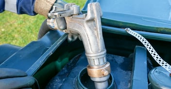 Person using a manual hand pump to fill a residential fuel tank.