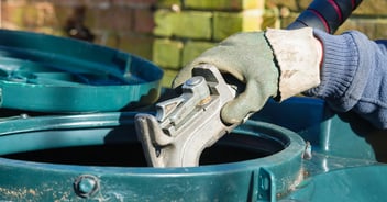 A of a worker's hands wearing gloves while they fill a heating oil tank at a residential property.