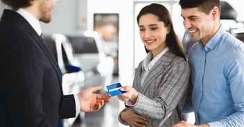 Happy couple buying a car from an auto dealership.