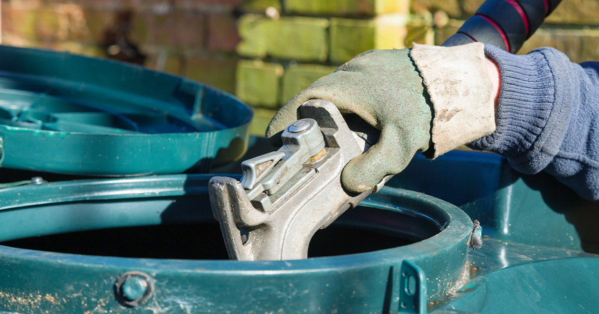 A of a worker's hands wearing gloves while they fill a heating oil tank at a residential property.